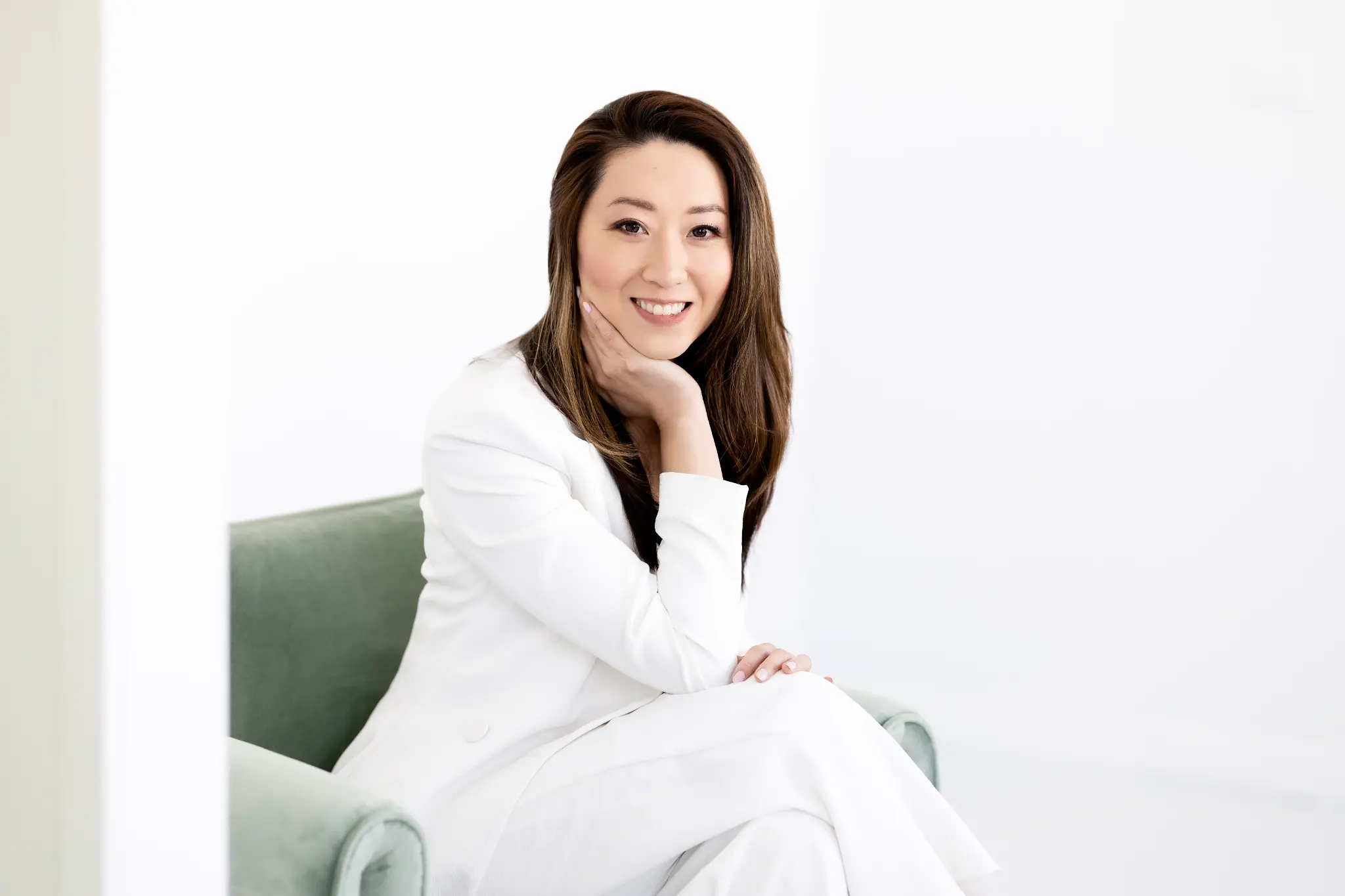 Manique in a white suit seated in an armchair
